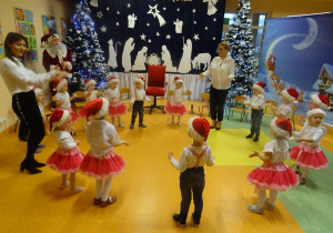 Pani dyrektor Maria Królikowska i pani Ewelina Cicha tańczą z dziećmi w kole.